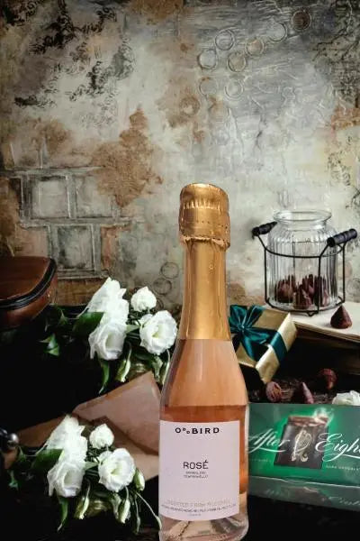 OBird Rose champanje liten og andre gaver i bakgrunnen